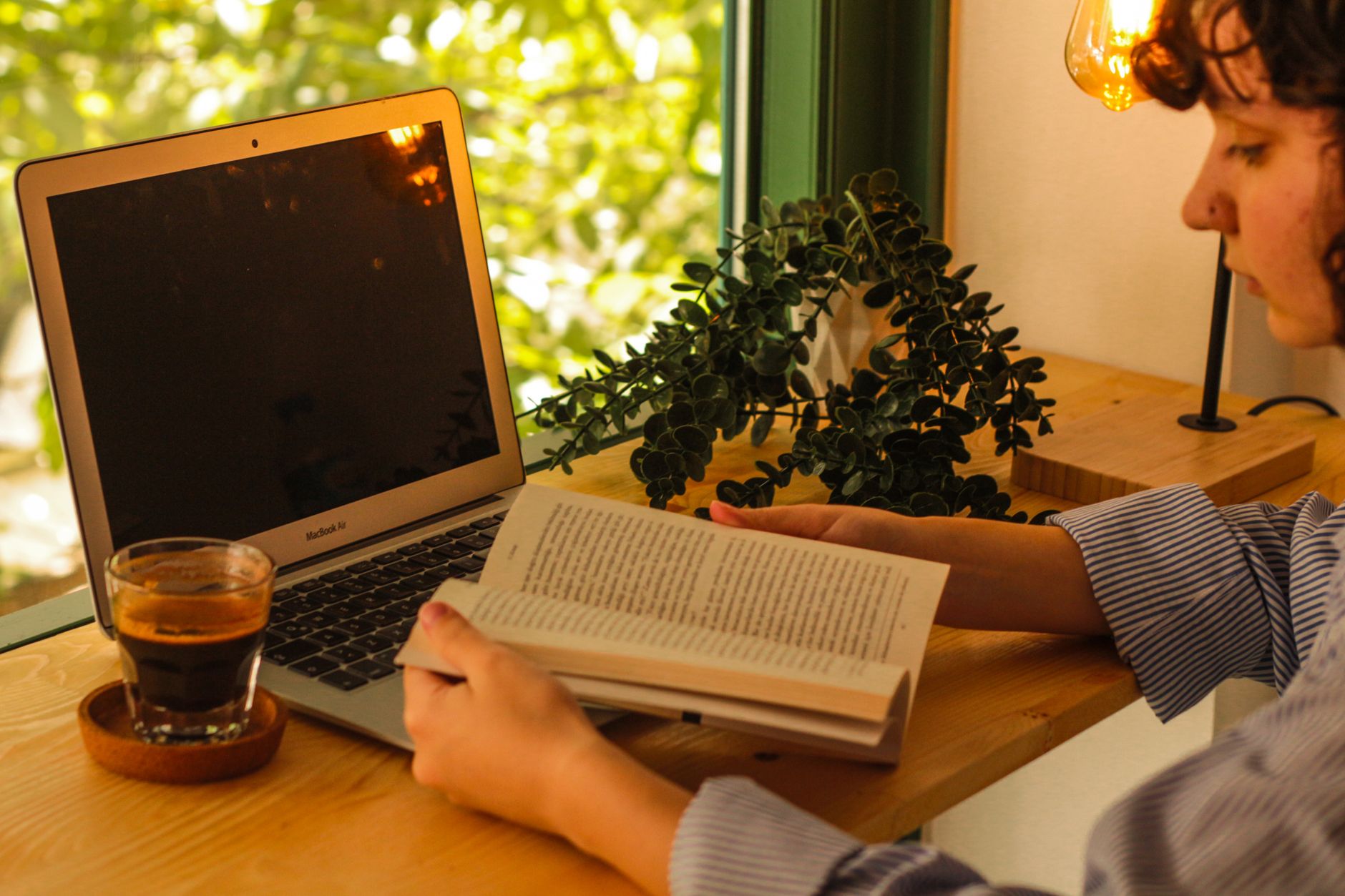 Un ambiente de trabajo cálido con un portátil, café y un libro, creando un espacio de estudio acogedor.